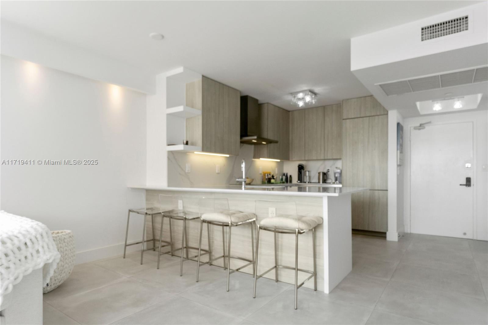 100 Lincoln Road, Unit 1411 Miami Beach, FL 33139 - Photo 4 of 36 a kitchen with stainless steel appliances a sink a stove a refrigerator cabinets and a dining table with wooden floor