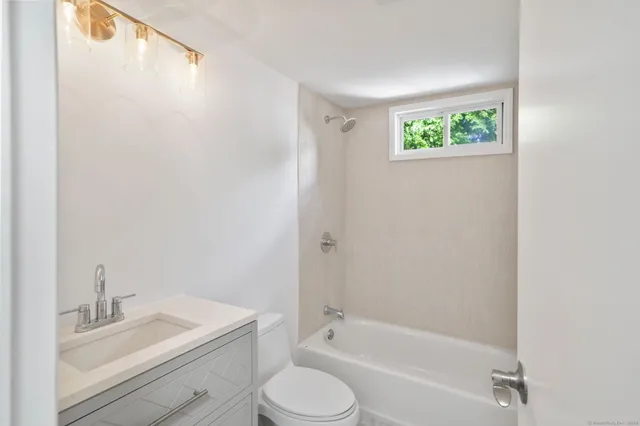 a bathroom with a granite countertop bathtub shower sink vanity and toilet