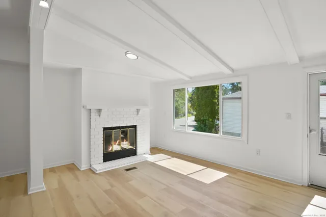 a view of an empty room with a fireplace and a window
