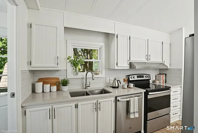 a view of a kitchen and an empty room with wooden floor and a kitchen