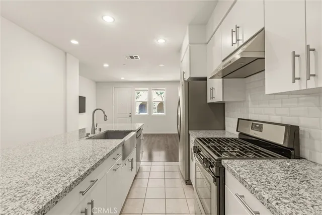 a kitchen with stainless steel appliances granite countertop a sink stove and cabinets