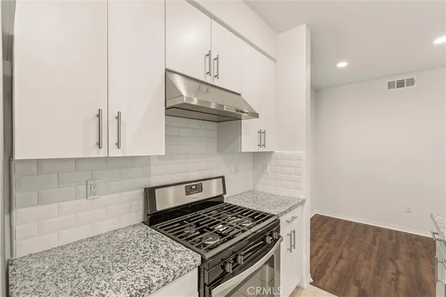 a kitchen with white cabinets and a stove top oven