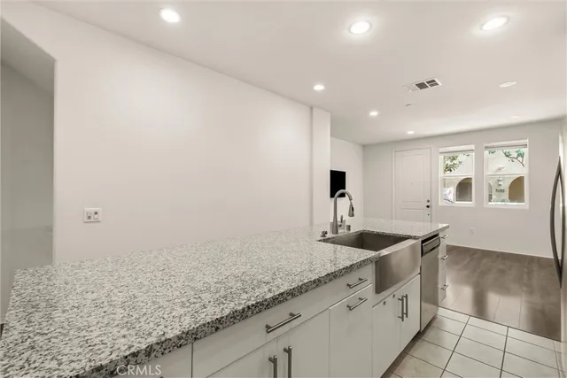a kitchen with granite countertop a sink and a white cabinets