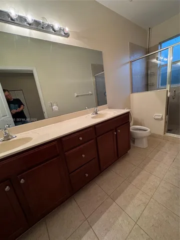 a bathroom with a double vanity sink a toilet and a mirror
