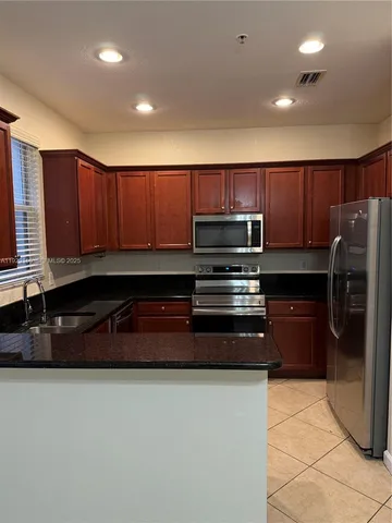 a kitchen with kitchen island granite countertop a stove and a refrigerator