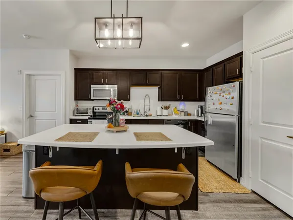 a kitchen with stainless steel appliances a table chairs and refrigerator