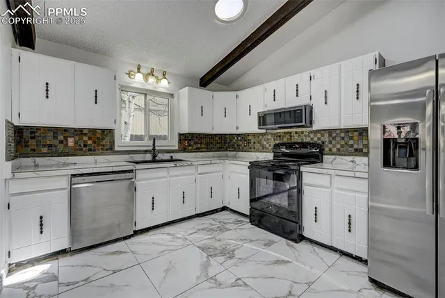 a kitchen with granite countertop white cabinets and stainless steel appliances