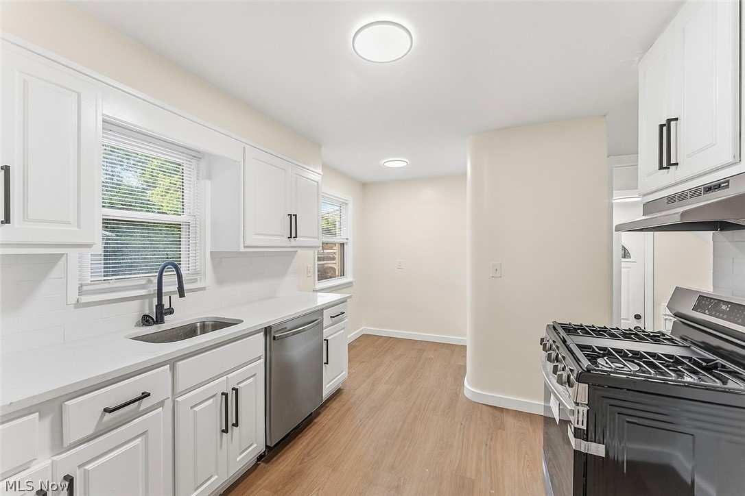 3791 Fairoaks Road South Euclid, OH 44121 - Photo 10 of 30 Modern kitchen featuring white cabinetry with black hardware, white countertops, stainless steel dishwasher, and wood-finish flooring