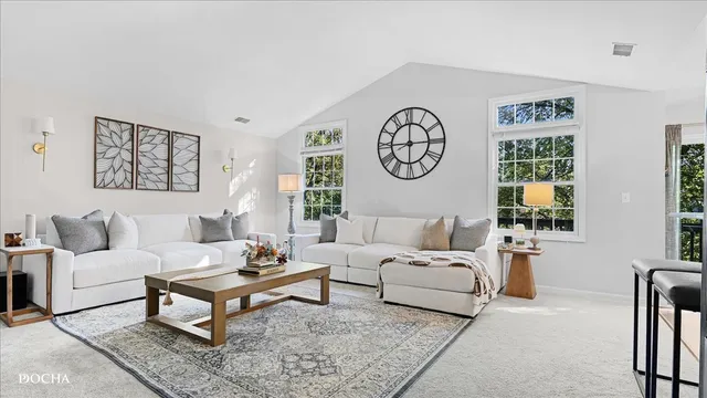 a living room with furniture a clock on wall and a window