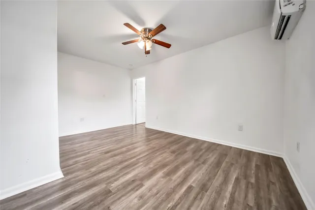 an empty room with wooden floor and a ceiling fan