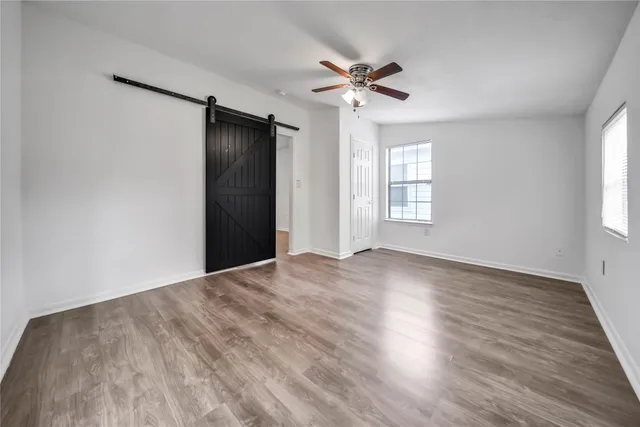 a view of empty room with wooden floor and fan