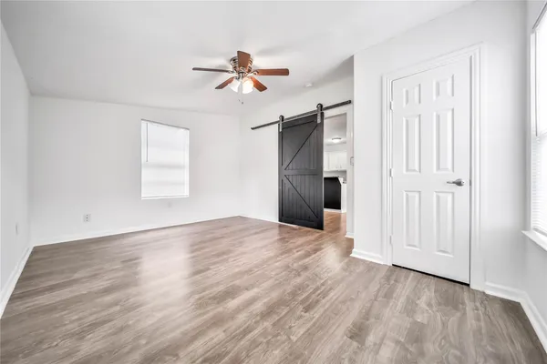an empty room with wooden floor closet and windows