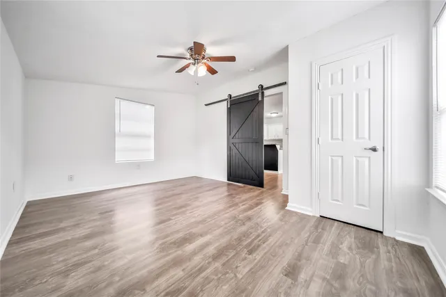 an empty room with wooden floor closet and windows