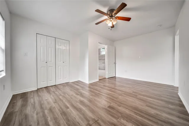 an empty room with wooden floor and ceiling fan