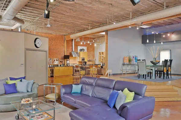 a dining hall with stainless steel appliances kitchen island granite countertop a table chairs stove and refrigerator