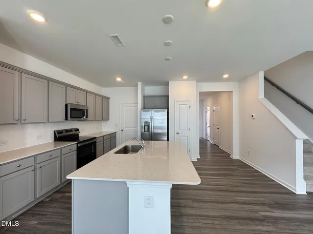 a large kitchen with stainless steel appliances kitchen island a stove a sink dishwasher and a refrigerator with wooden floor