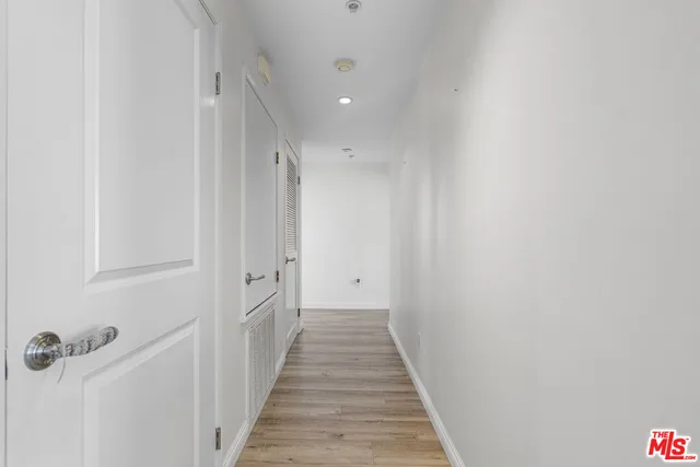 a view of a hallway with wooden floor and closet