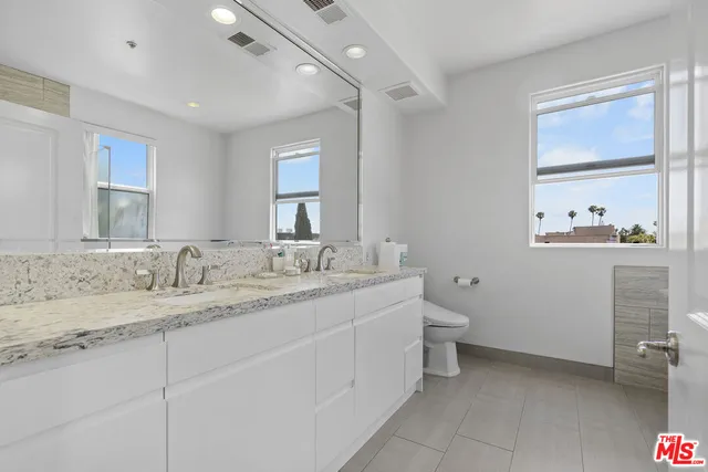 a bathroom with a granite countertop toilet sink and mirror