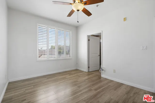 an empty room with wooden floor chandelier fan and windows