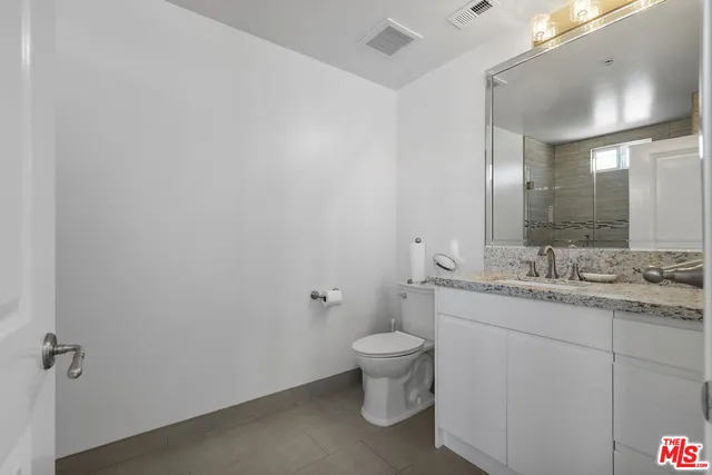 a bathroom with a granite countertop toilet and a sink