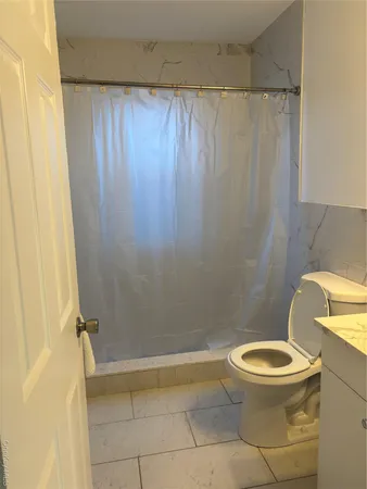 a white toilet sitting next to a shower