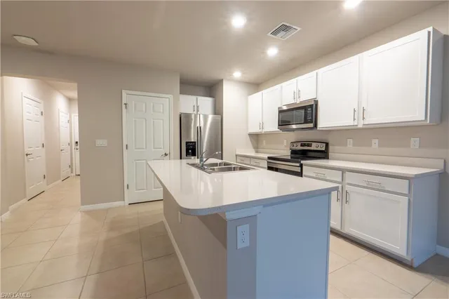 a kitchen with kitchen island granite countertop a sink appliances cabinets and furniture