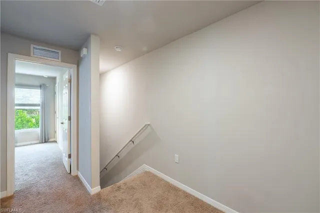 a view of an empty room with chandelier fan and fire place