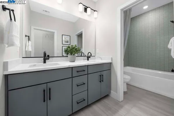 a bathroom with a double vanity sink toilet mirror and bathtub