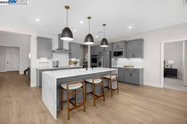 a kitchen with stainless steel appliances a sink a stove a refrigerator cabinets and chairs