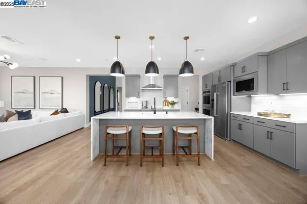 a kitchen with stainless steel appliances kitchen island granite countertop a table chairs sink and cabinets