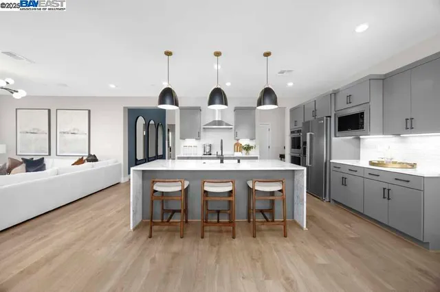 a kitchen with stainless steel appliances kitchen island granite countertop a table chairs sink and cabinets