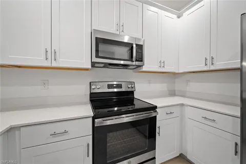 a kitchen with white cabinets and black appliances