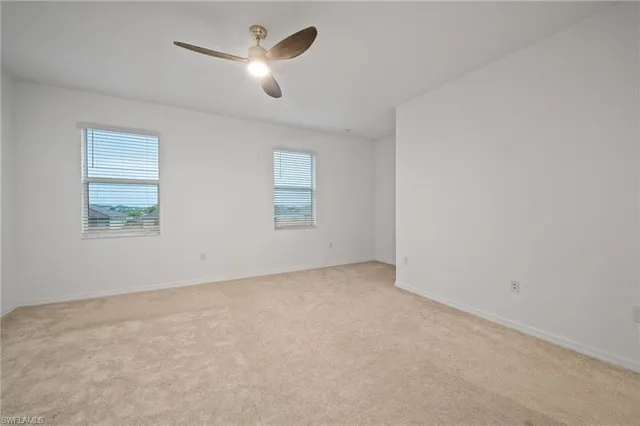 an empty room with a chandelier fan and windows