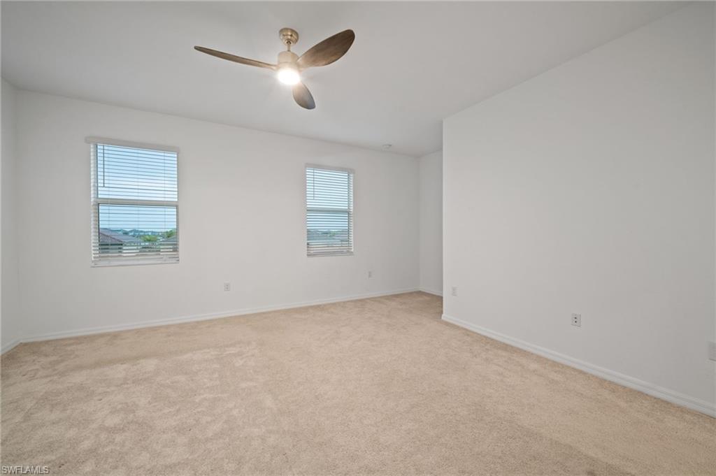 2878 Blossom Way Naples, FL 34120 - Photo 24 of 41 an empty room with a chandelier fan and windows