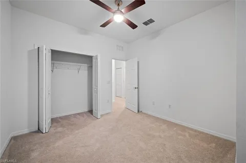 an empty room with ceiling fan and window