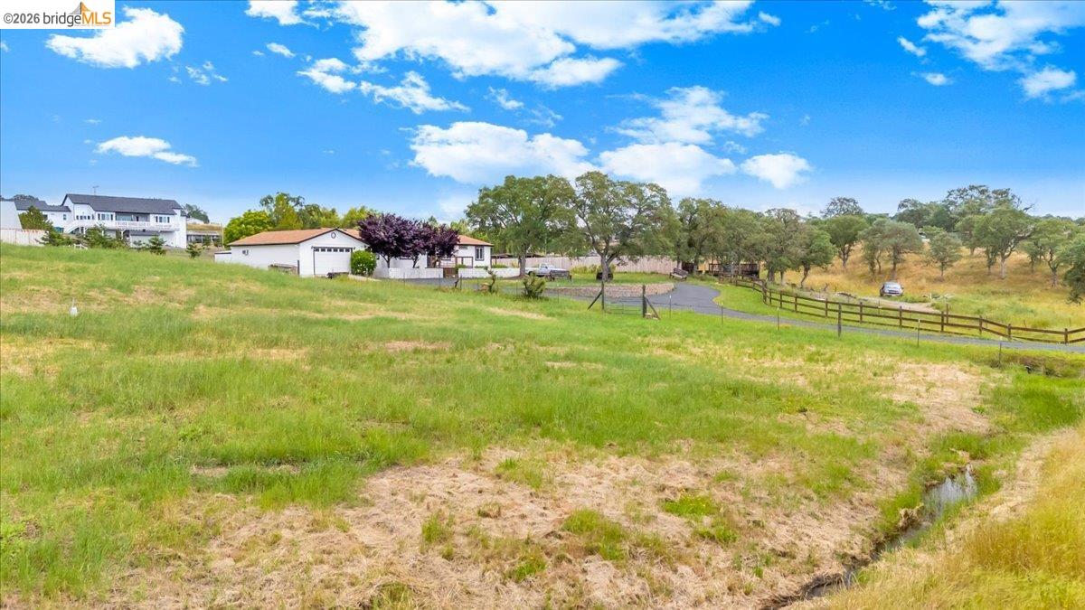 4419 Little John Road Copperopolis, CA 95228 - Photo 32 of 43 Expansive grassy lot featuring a country fence line, mature trees, and a visible stream
