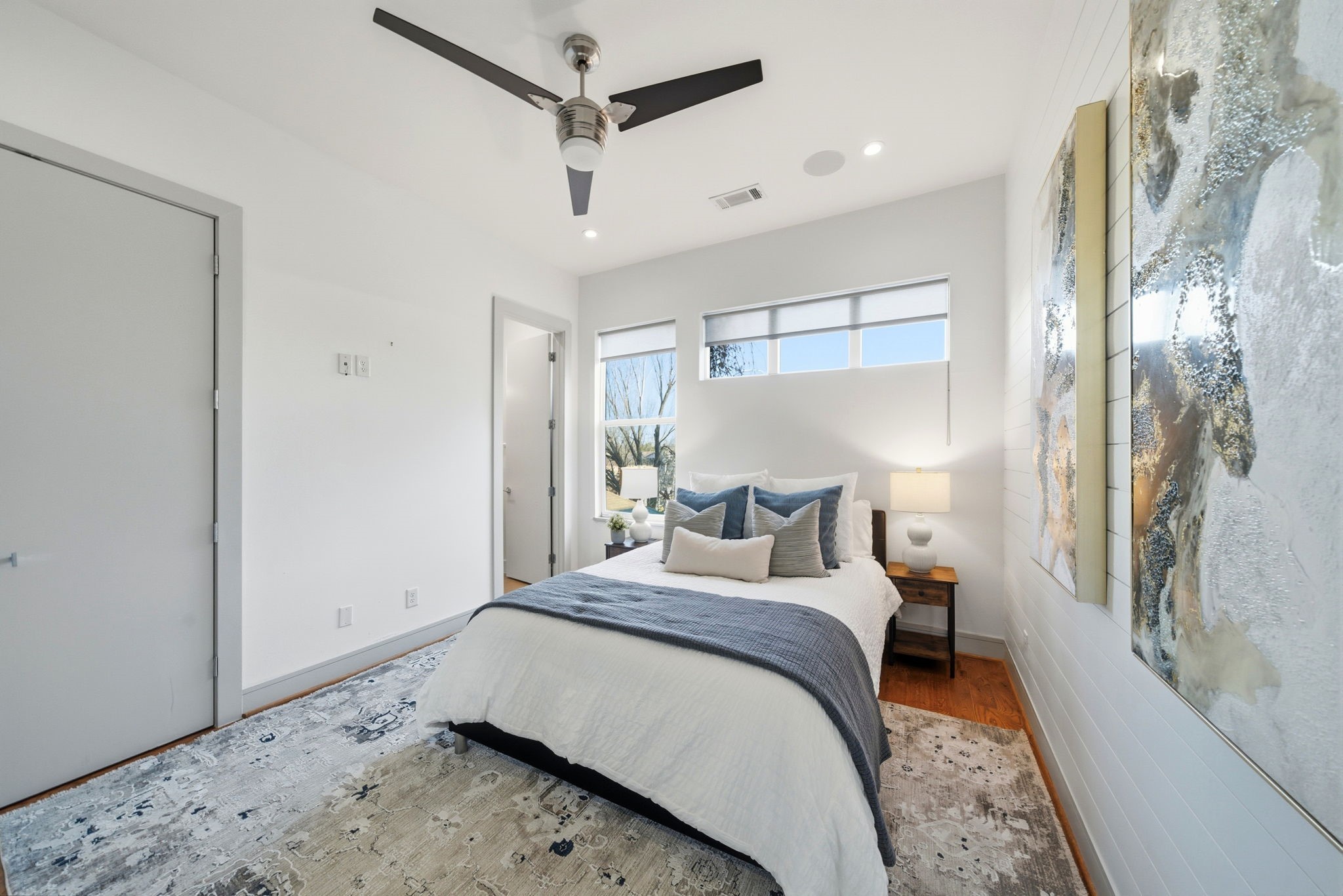 1405 Vermont Street, Unit A Houston, TX 77006 - Photo 33 of 46 Light-filled first-floor guest suite features polished hardwoods and high ceilings, creating an inviting sanctuary for visitors. Dual windows provide peaceful treetop views, while a contemporary ceiling fan and designer neutral palette enhance the airy atmosphere. This spacious retreat offers seamless access to a renovated ensuite bath, ensuring a private and luxury experience for guests.