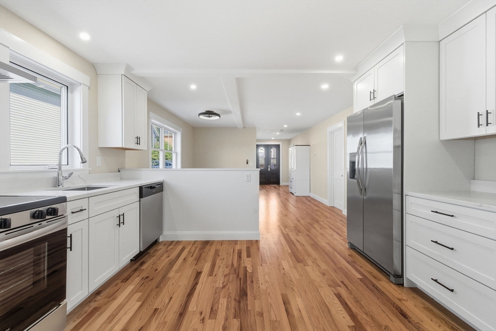 a large kitchen with stainless steel appliances granite countertop a lot of counter space and wooden floor