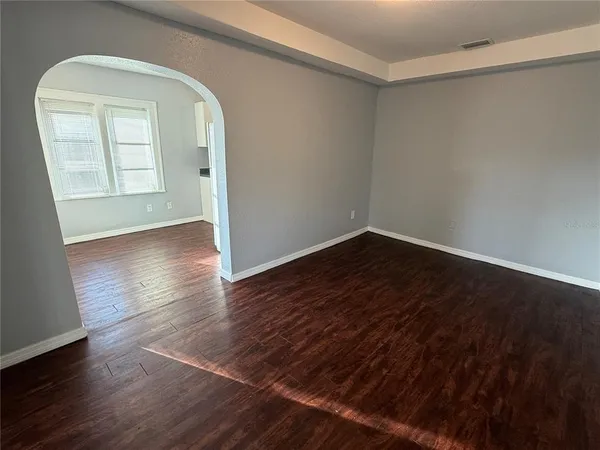 an empty room with wooden floor cabinet and windows