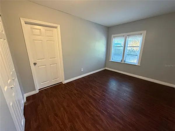 a view of an empty room with wooden floor and a window