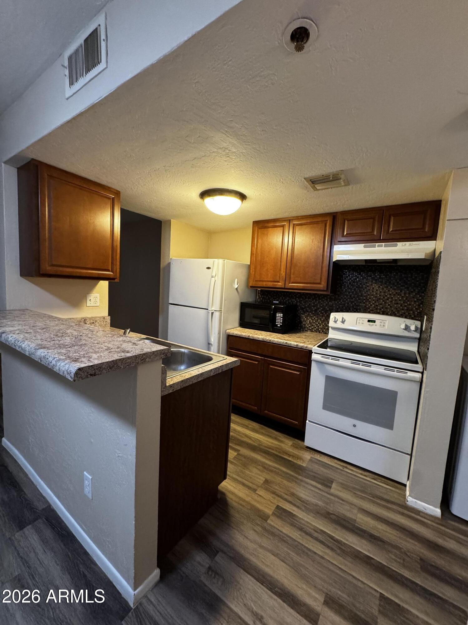 12123 West Bell Road, Unit 258 Surprise, AZ 85378 - Photo 6 of 30 a kitchen with stainless steel appliances kitchen island granite countertop a stove and a sink