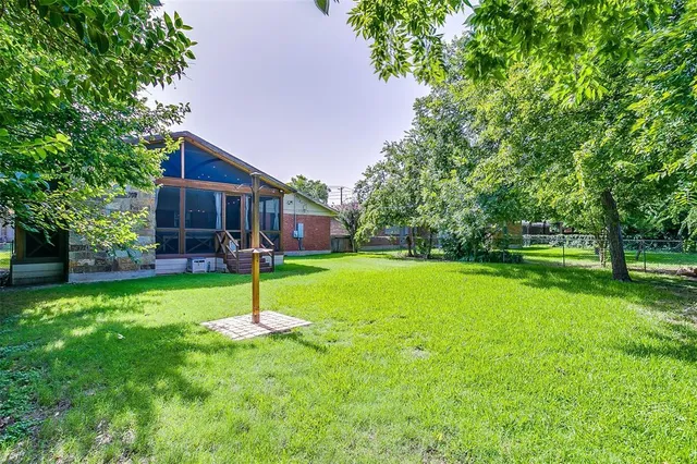 a house with a big yard and potted plants and large trees