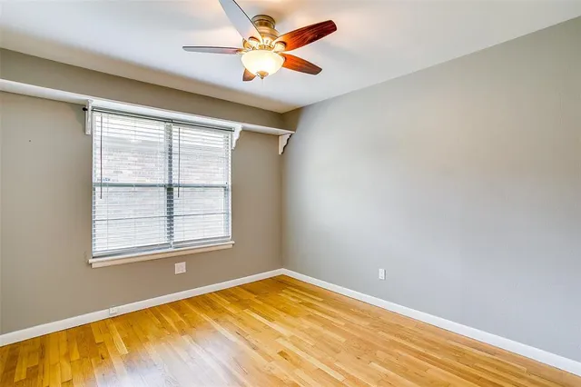 a view of an empty room with window and chandelier fan