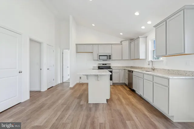 a kitchen with wooden floors stainless steel appliances and white cabinets
