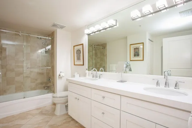 a bathroom with a double vanity sink toilet mirror and shower