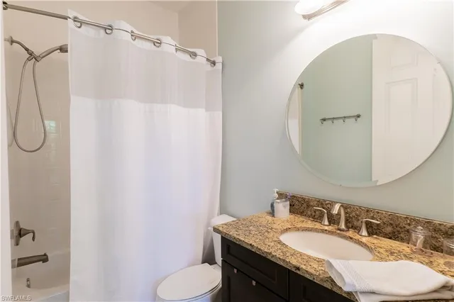 a bathroom with a granite countertop sink toilet and a mirror