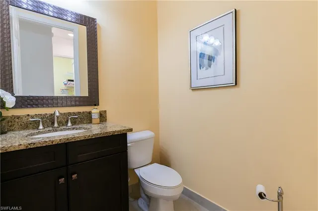 a bathroom with a granite countertop toilet a sink and mirror