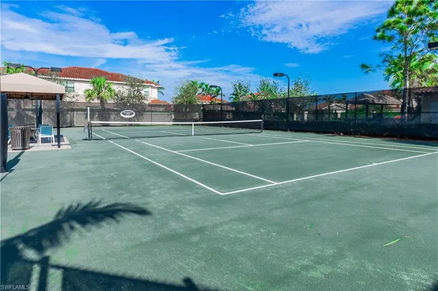 a view of a tennis ground with large trees