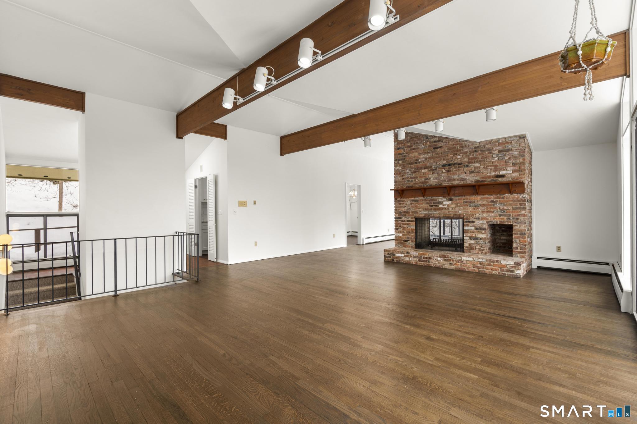 a view of empty room with wooden floor and fireplace