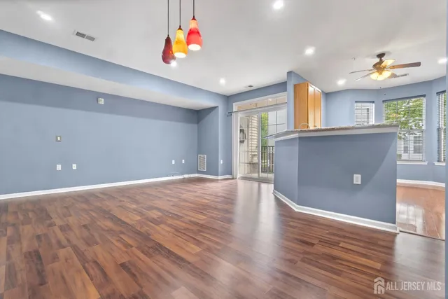 a view of an empty room with window and wooden floor